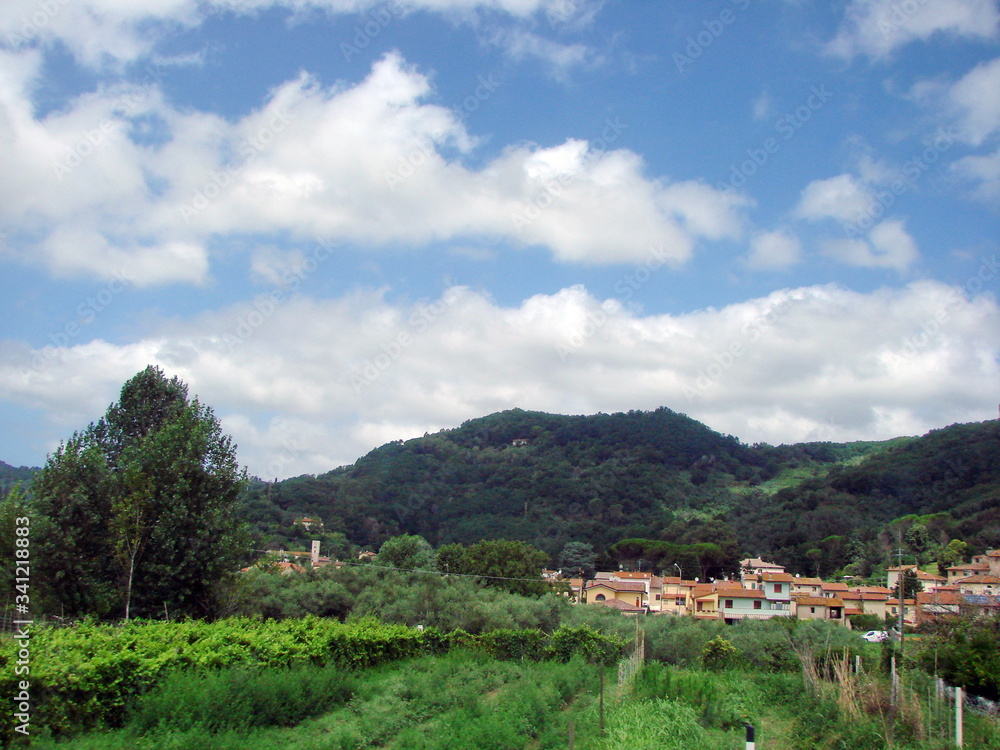 Panorama of green hills in the outskirts of Florence on a background of blue barely cloudy sky.