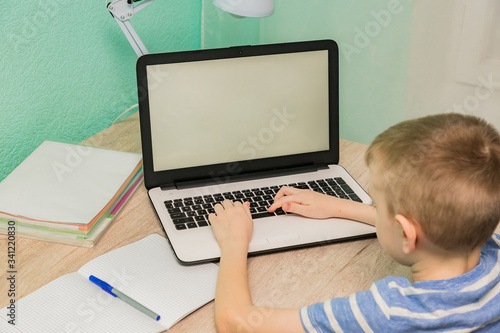 Distance learning online education. Schoolboy studying at home with laptop notebook and doing school homework.