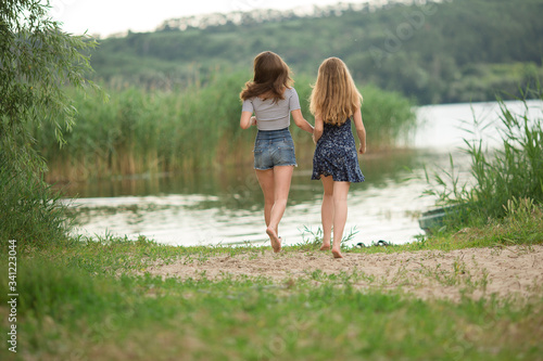 girls with long hair running to the lake, tourists