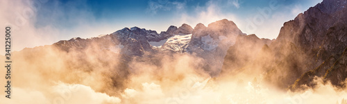 Dachstein Panorama mit stimmungsvollen Wolken im Vordergrund und blauem Himmel