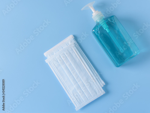 Surgical mask for wearing germ protection  and gel alcohol or hand sanitizer  bottle for washing hand  to protect from corona cirus set on blue background,top view photo