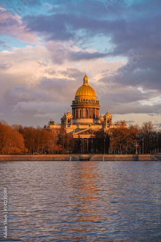 Embankment with a view of St. Isaac's Cathedral and the arch in the sunset rays of the sun, beautiful evening sky, the Neva river