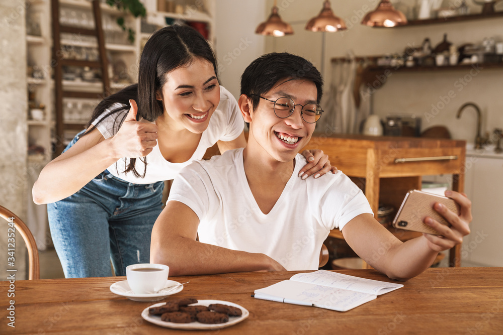Image of couple taking selfie on smartphone and gesturing thumb up Image of couple taking selfie on smartphone and gesturing thumb up