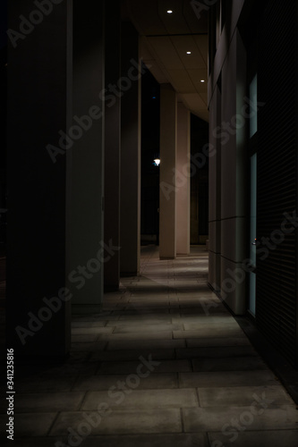 Shadowy city walkway next to modern building at night