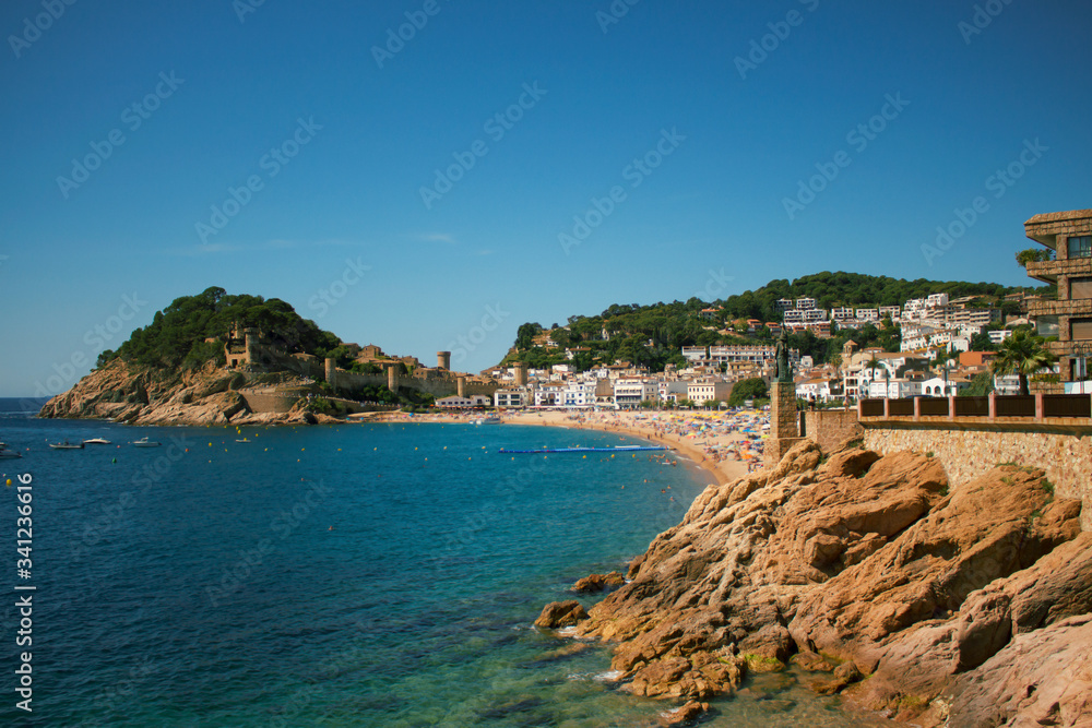 View of the tourist city in Spain with a beach, a fortress and stones.