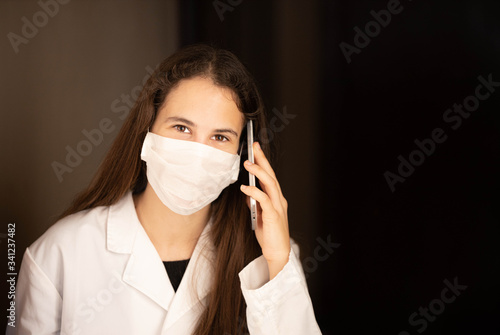 Happy sick woman with mask and gown talking on mobile