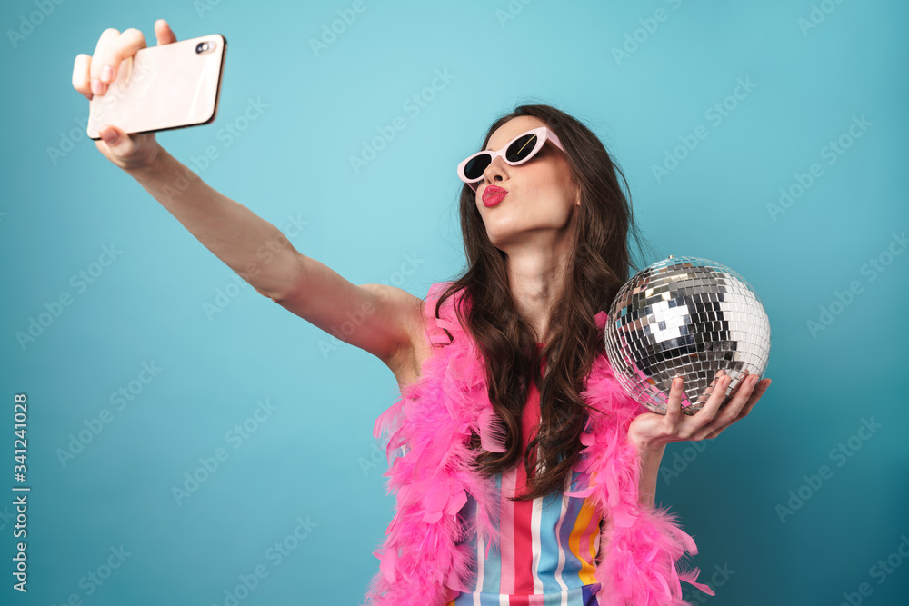© Drobot Dean - Photo of woman holding disco ball whiletaking selfie on cellphone