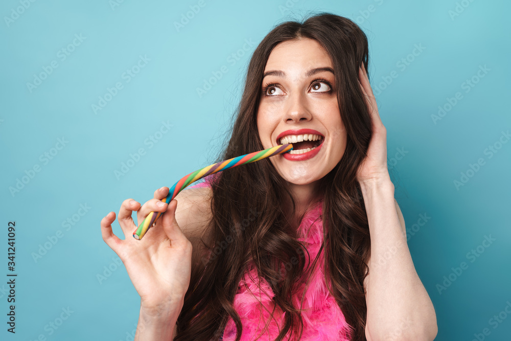 Photo of joyful woman in feather boa smiling and eating candy Photo of joyful woman in feather boa smiling and eating candy