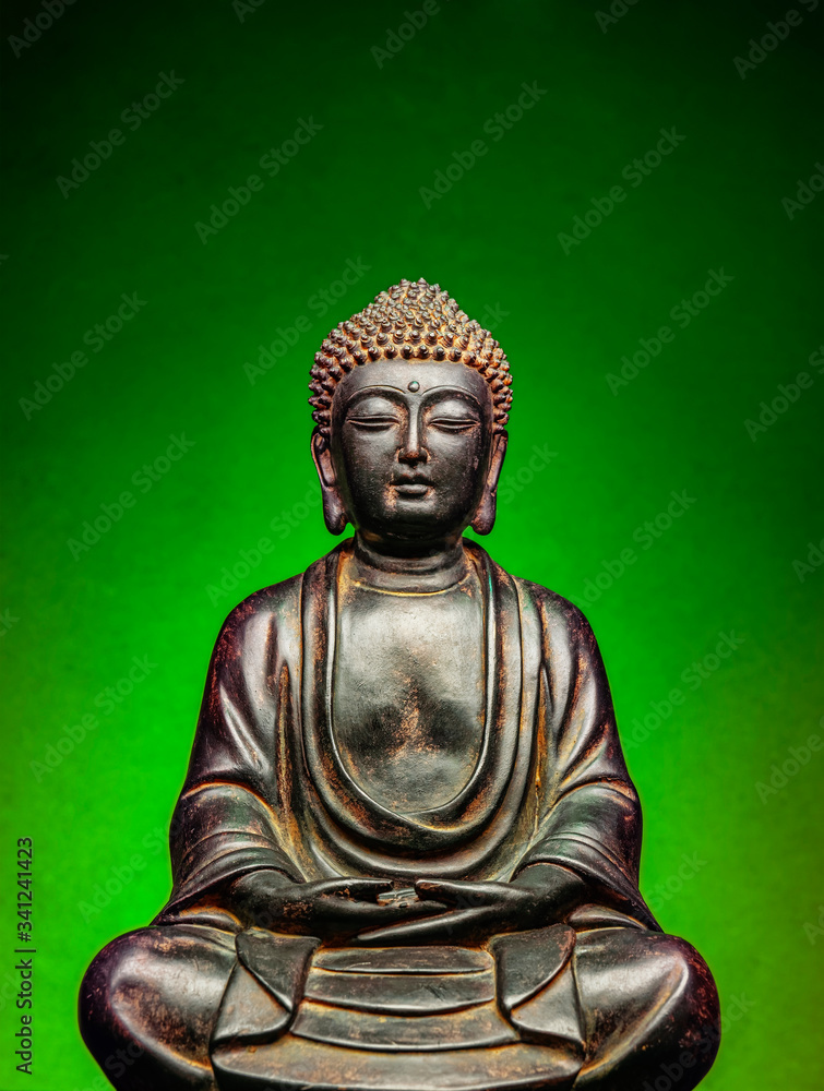 A small replica statue of The Buddha with a green background.  Green symbolizing cleanliness and purity from contamination.