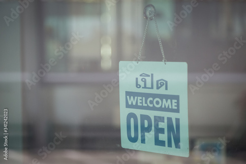 Open and welcome sign broad through the glass of window