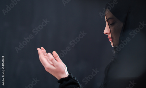 muslim woman making traditional prayer to God in front of black chalkboard