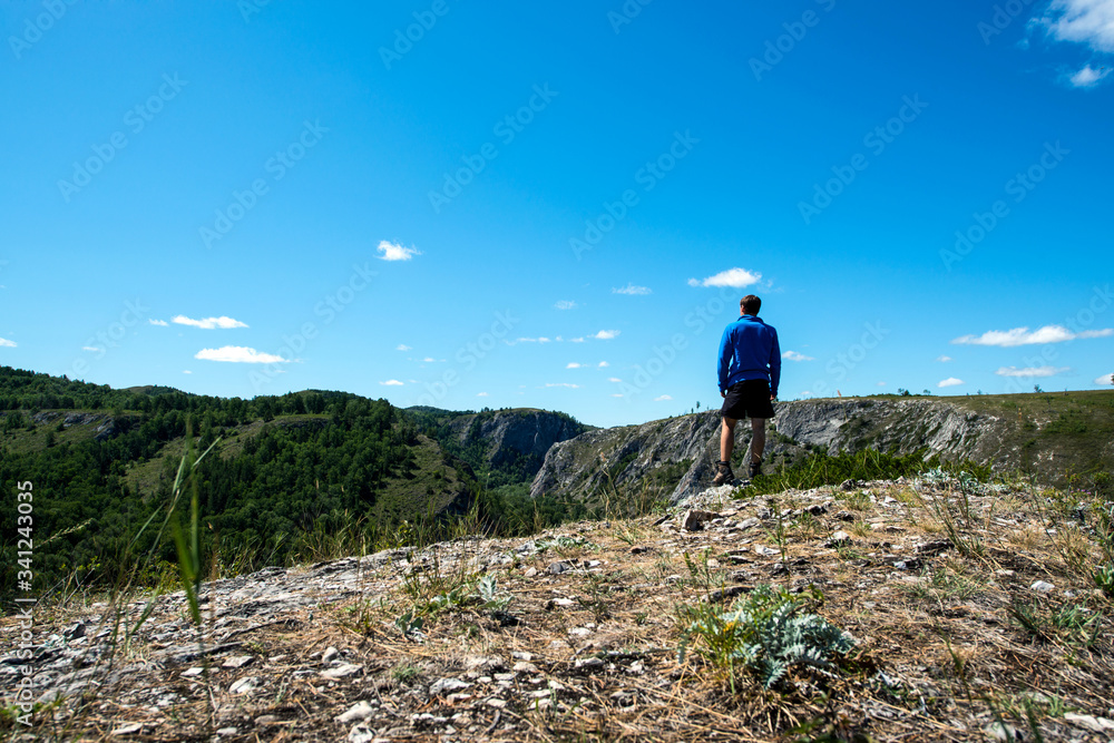 a male tourist stands on the top of a mountain and looks into the distance at the mountains