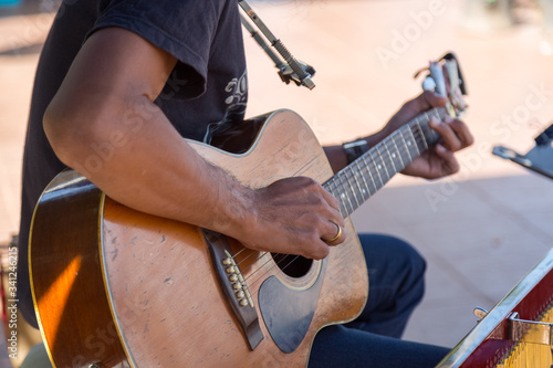 Hipster playing a old wood guitar in happy moment with blur background