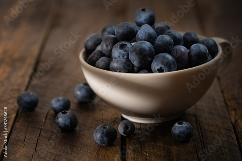 Cup of fresh blueberry fruit in dark and moody lighting