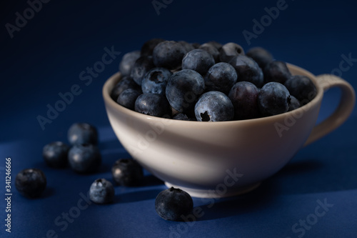 Cup of fresh blueberry fruit in dark and moody lighting