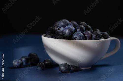 Cup of fresh blueberry fruit in dark and moody lighting