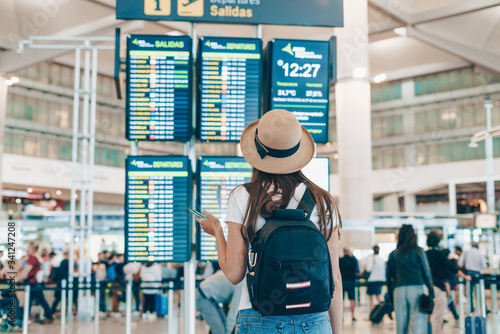 at the airport, the girl stands with her back to the camera and looks at the departure board.