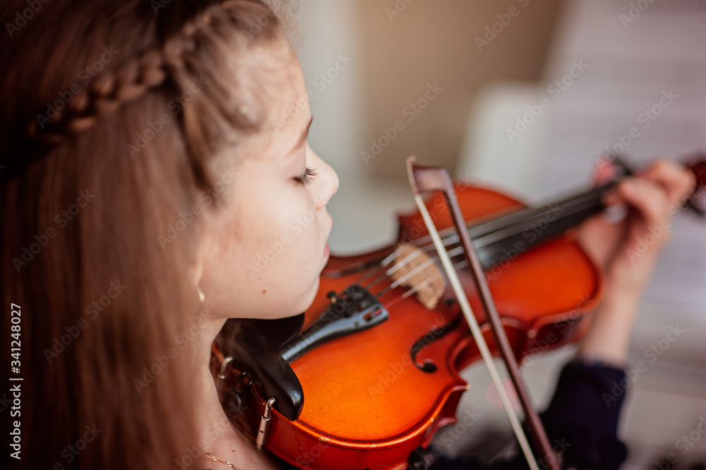 Home lesson for a girl playing the violin. The idea of activities for children during quarantine. Music concept Home lesson for a girl playing the violin. The idea of activities for children during quarantine. Music concept