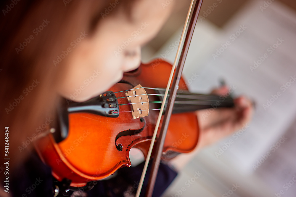 Home lesson for a girl playing the violin. The idea of activities for children during quarantine. Music concept Home lesson for a girl playing the violin. The idea of activities for children during quarantine. Music concept