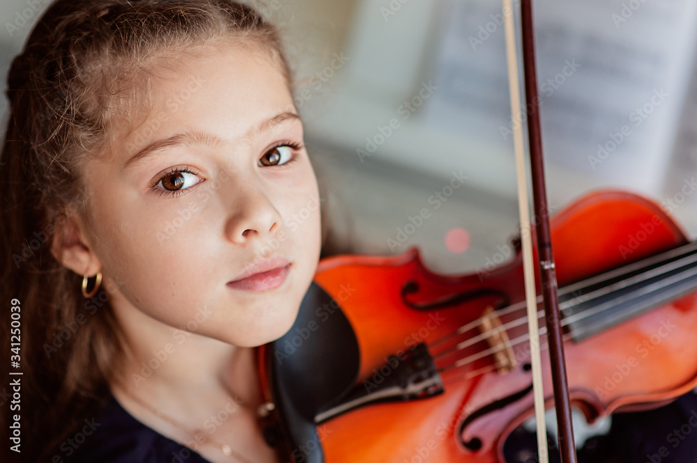 Home lesson for a girl playing the violin. The idea of activities for children during quarantine. Music concept Home lesson for a girl playing the violin. The idea of activities for children during quarantine. Music concept