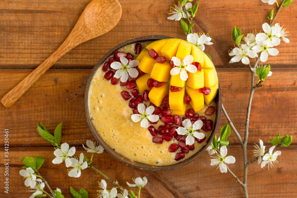 mango smoothie with banana and almonds in a coconut bowl and bamboo spoon, vegan breakfast, healthy diet food mango smoothie with banana and almonds in a coconut bowl and bamboo spoon, vegan breakfast, healthy diet food