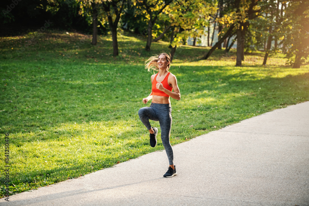 Fototapeta premium Full length of young handsome slim sportswoman with healthy habits running in nature in the morning.