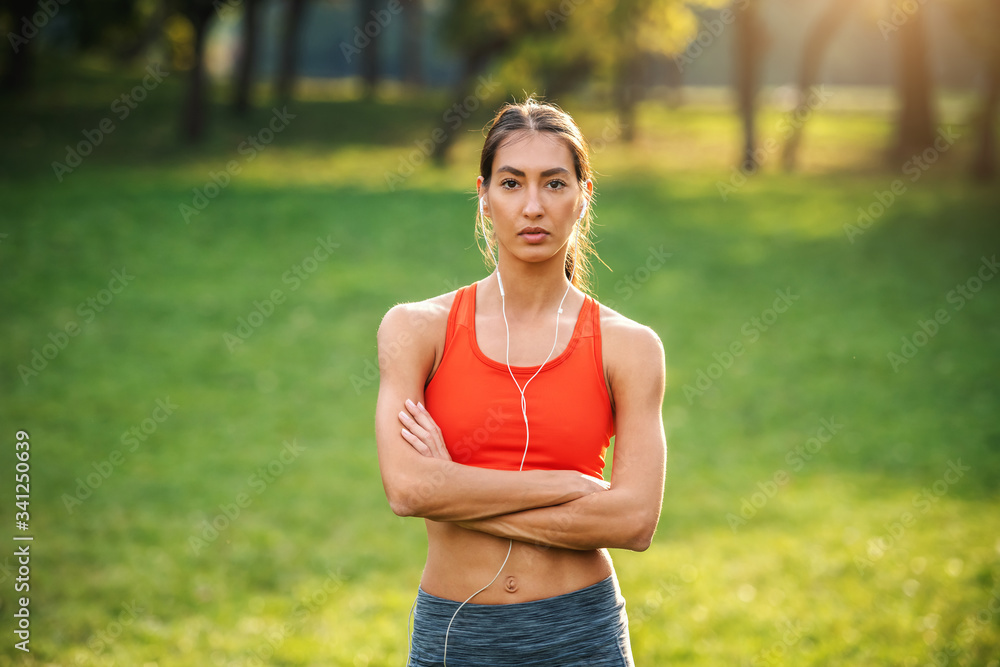 Young slim fit gorgeous pensive sportswoman standing in nature with arms crossed. Young slim fit gorgeous pensive sportswoman standing in nature with arms crossed.