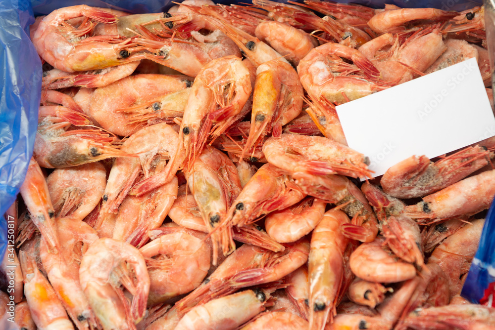 A lot of frozen boiled shrimp lies in a box.