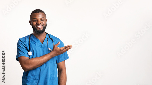 Friendly african american doctor pointing at free space