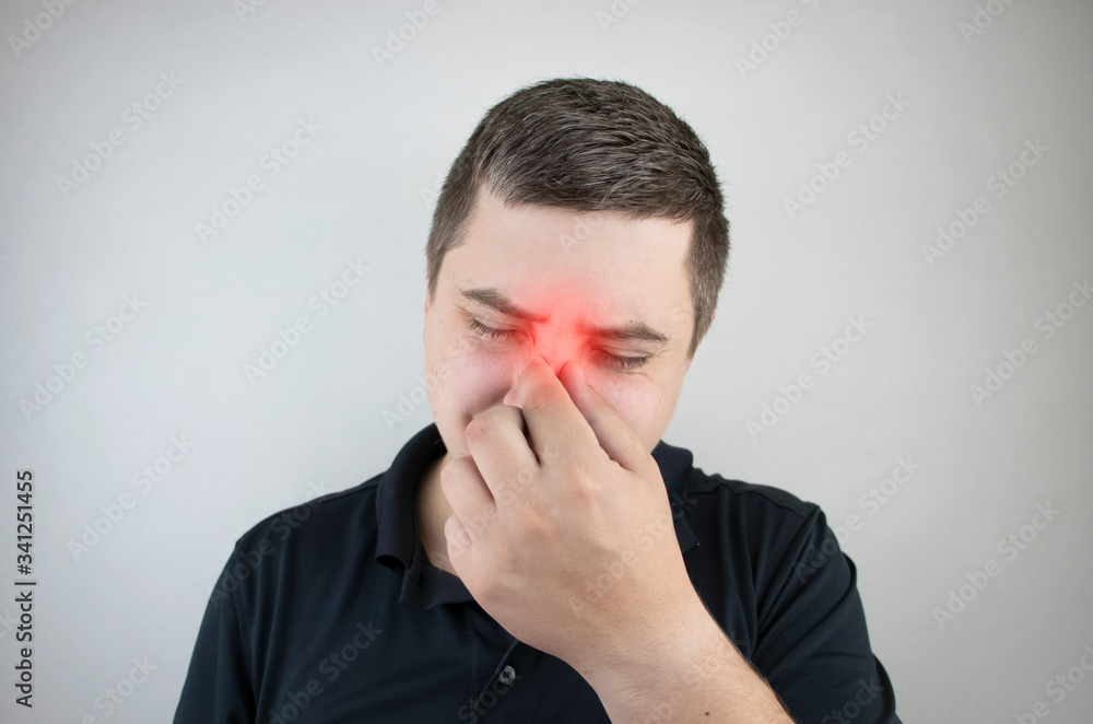 Nasal bridge pain, headache. A man holds his nose with his hand and winces in pain. Signs of acute ethmoiditis Nasal bridge pain, headache. A man holds his nose with his hand and winces in pain. Signs of acute ethmoiditis