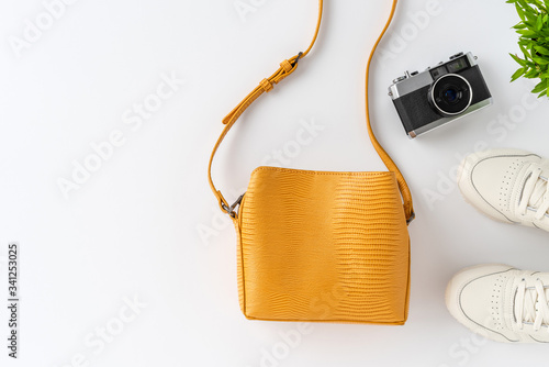 Woman’s lifestyle background with camera photo, purse and sneakers. Top view