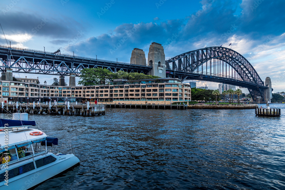 Sydney, Australia - 10th February 2020: A German photographer visiting Sydney in Australia, taking pictures of an area called The Rocks with the Harbour Bridge during a cloudy but warm day in summer.