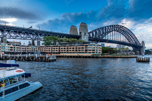 Sydney, Australia - 10th February 2020: A German photographer visiting Sydney in Australia, taking pictures of an area called The Rocks with the Harbour Bridge during a cloudy but warm day in summer. © ms_pics_and_more