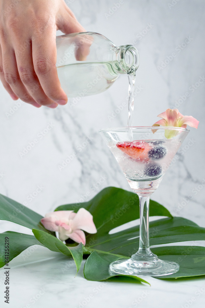 Close up hand, the bartender is mixing soda with strawberries and blueberries in a glass to prepare a cocktail on the green leaves.Food and beverage ideas and copy space. Close up hand, the bartender is mixing soda with strawberries and blueberries in a glass to prepare a cocktail on the green leaves.Food and beverage ideas and copy space.