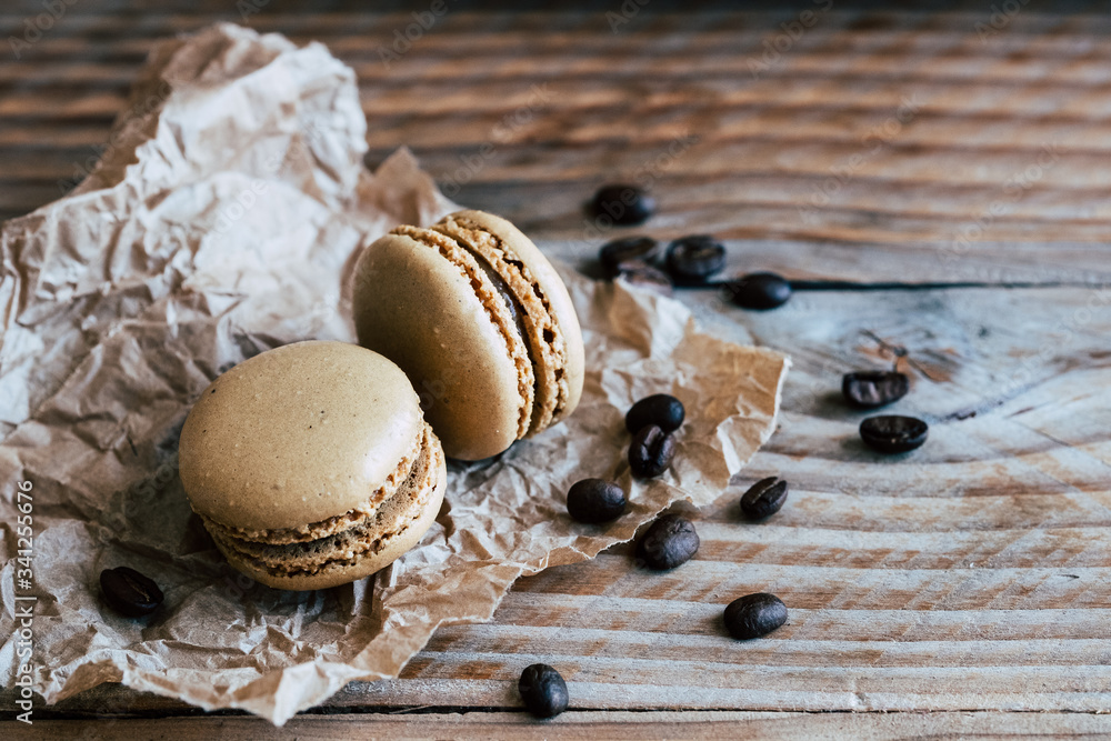 Deux macarons au café et grains de café sur une table en bois Deux macarons au café et grains de café sur une table en bois