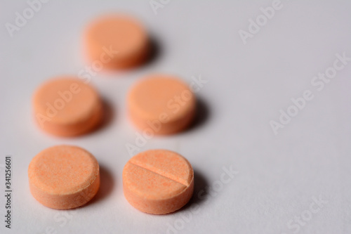 Orange color tablet pills on gray background.