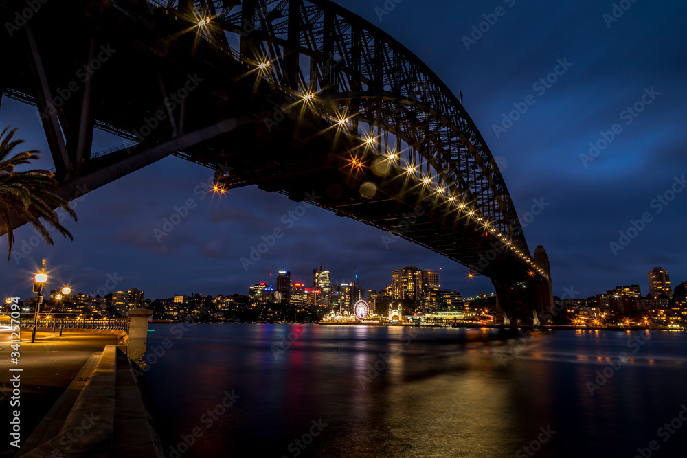 Obraz premium Sydney, Australia - 12th February 2020: A German photographer visiting Sydney in Australia, taking pictures of the Harbour Bridge at night with the Lunar park in the background.