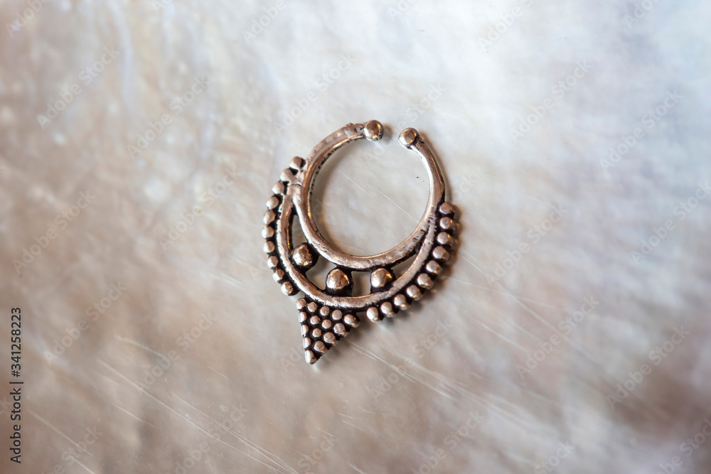 Metal nose decorative septum oriental boho jewelry on natural white shell background Metal nose decorative septum oriental boho jewelry on natural white shell background