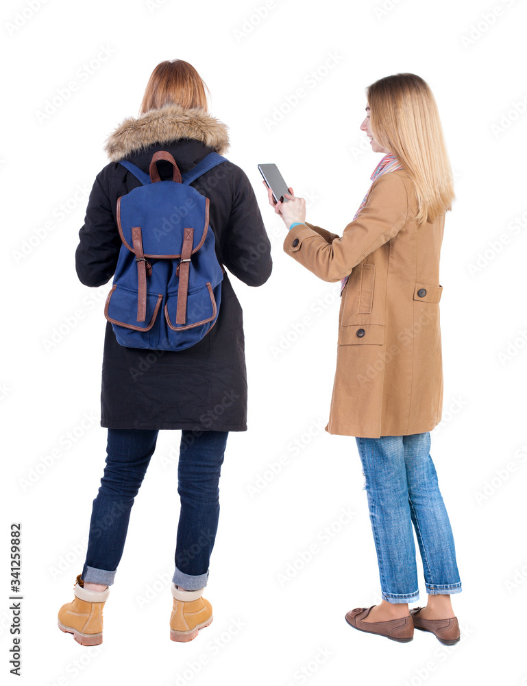 Back view of two young woman photographed on a mobile phone in winter jacket. Back view of two young woman photographed on a mobile phone in winter jacket.