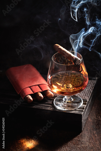 Smoking cigar and whisky on old humidor