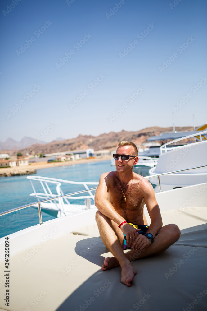 Successful guy sit on a white yacht with sea view. Red sea, bright sun