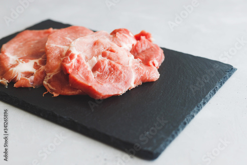 Raw fresh pork stacks do not lie on a black stone board on a gray background. Save the space. Meat preparation