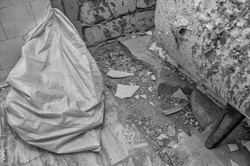 bag with construction waste during the repair in the apartment. dirt, tiles fragments, cement, bricks. black and white
