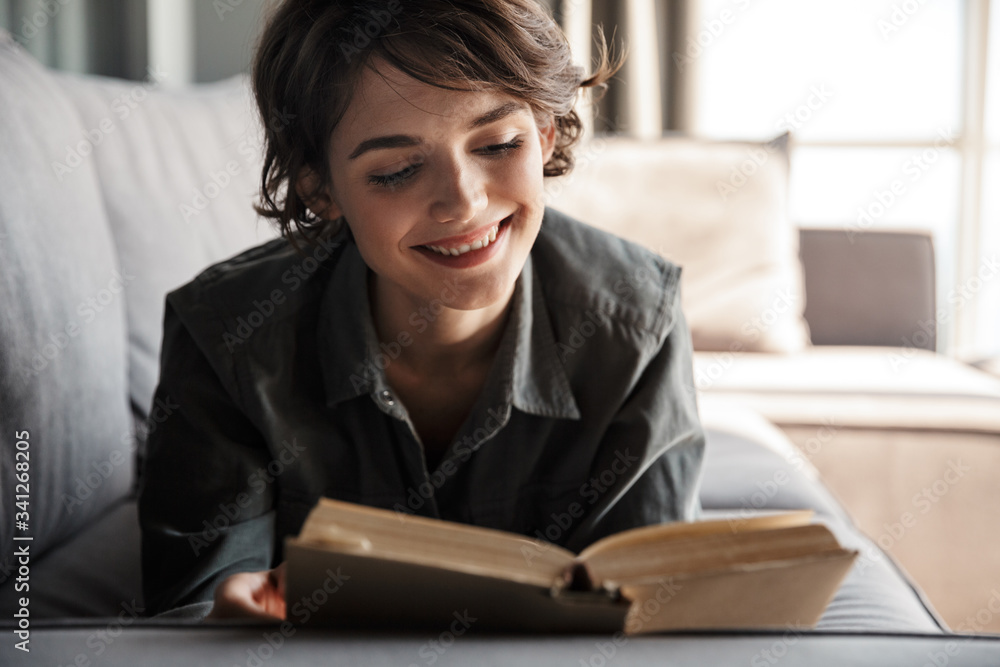Image of caucasian cute pleased woman reading book and smiling Image of caucasian cute pleased woman reading book and smiling