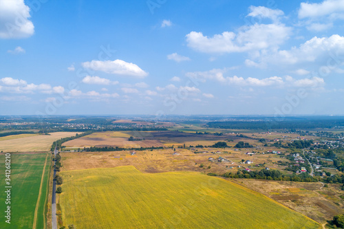 Rural landscape with a beautiful sky. Aerial view. View of plowed and green fields, and village in summer