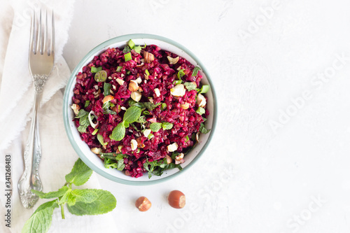 Warm buckwheat, beetroot, nuts and herbs salad, light grey concrete background. Vegetarian and vegan food. Healthy food concept. Top view.