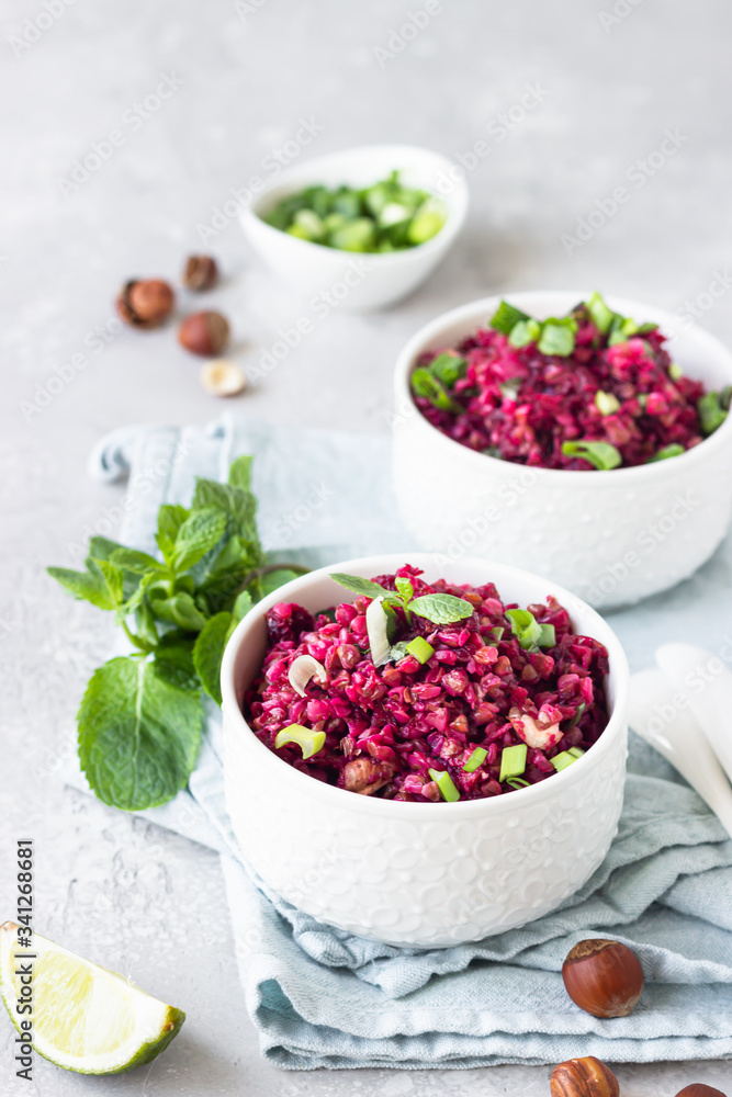 White ceramic bowls with buckwheat, beetroot, nuts and herbs warm salad, light grey concrete background. Dietary balanced food concept. Vegetarian and vegan meal. White ceramic bowls with buckwheat, beetroot, nuts and herbs warm salad, light grey concrete background. Dietary balanced food concept. Vegetarian and vegan meal.