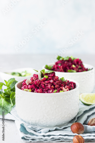 White ceramic bowls with buckwheat, beetroot, nuts and herbs warm salad, light grey concrete background. Dietary balanced food concept. Vegetarian and vegan meal. 
