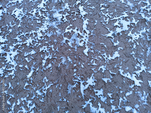 Top view on a background of gray earth with particles of white snow. Texture