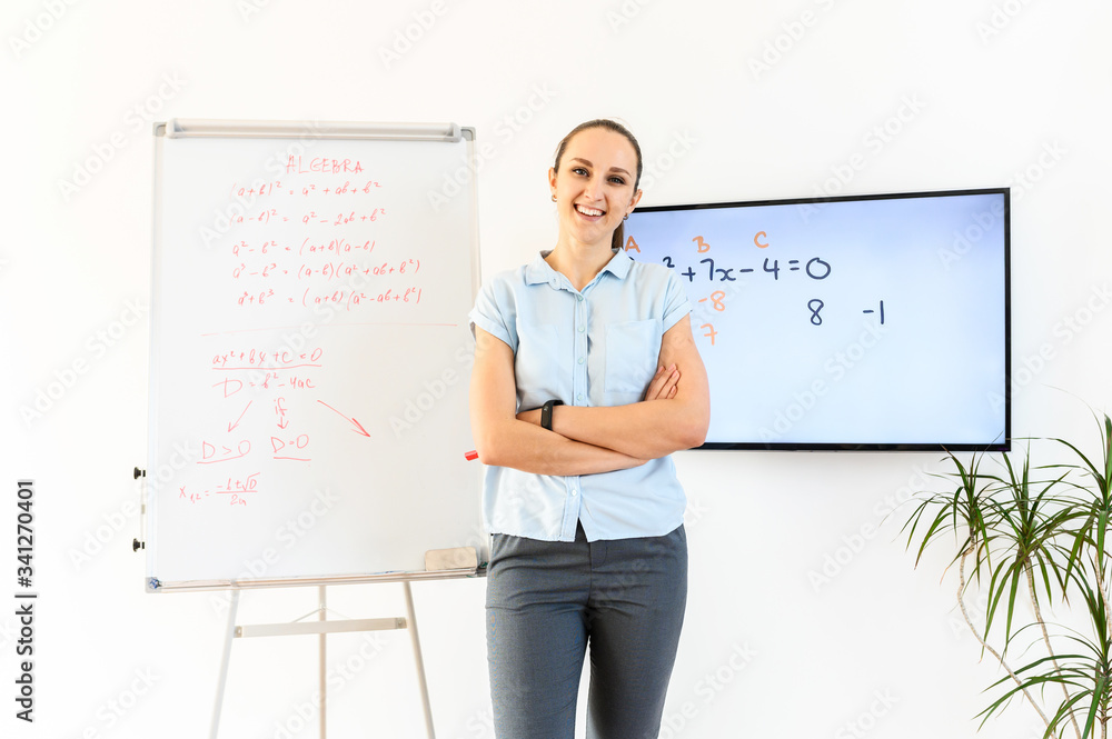 Distance study concept. A young female teacher, tutor is recording classes on a video. She is writing something on flipchart, camera on foreground Distance study concept. A young female teacher, tutor is recording classes on a video. She is writing something on flipchart, camera on foreground